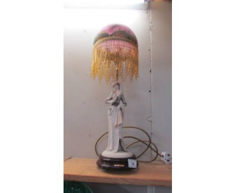 A figural table lamp with beaded shade.