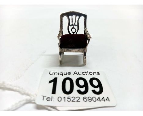 A small silver doll house chair with red seat.