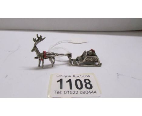 A small silver reindeer with sleigh.