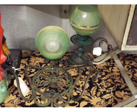 A wrought iron wall light together with a patinated brass table lamp both with art deco green glass shades 