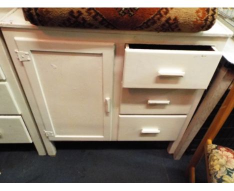 A vintage white painted kitchen cabinet having three drawers and cupboard door enclosing inner shelf space