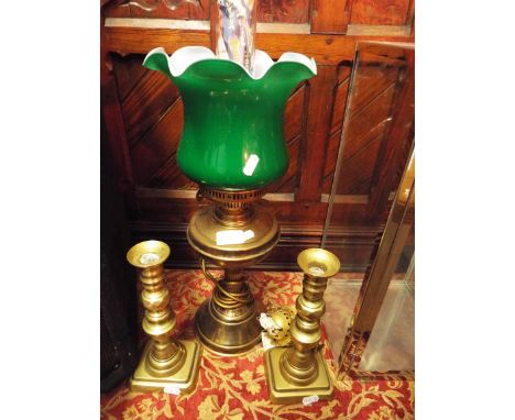A brass oil lamp with green glass shade converted to electricity together with a pair of 19thC brass candlesticks