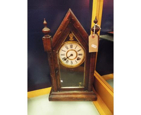 A walnut cased Gothic style mantel clock with brass bezel, enamel dial and Roman numerals and glass inspection panel below 