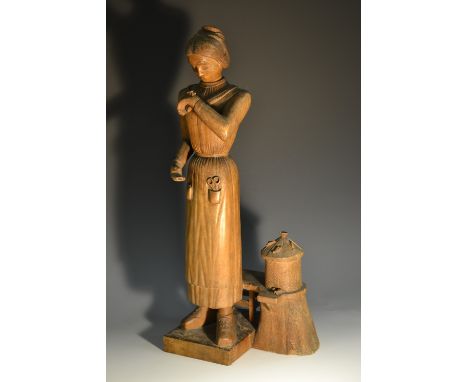 A 19th century Folk Art figure, carved as a bee keeper, she stands beside the skep, inspecting an insect on her hand, 50cm hi