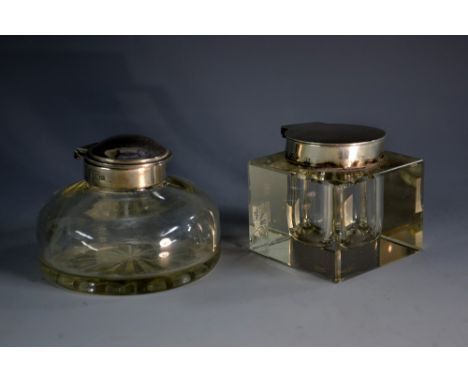 An Edwardian silver-mounted clear glass square inkwell, hinged cover. 5.5cm wide, London 1902; another, circular (2)