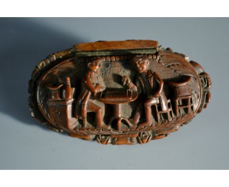 A late 18th/early 19th century coquilla nut snuff box, hinged cover carved with gentleman at play in a tavern, the base with 
