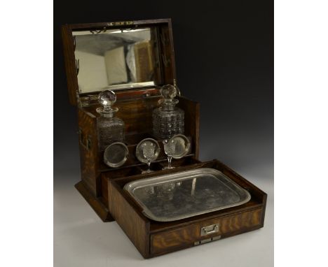 A Victorian oak gentleman's library tantalus, hinged cover and fall front enclosing decanters, serving trays, cribbage board 