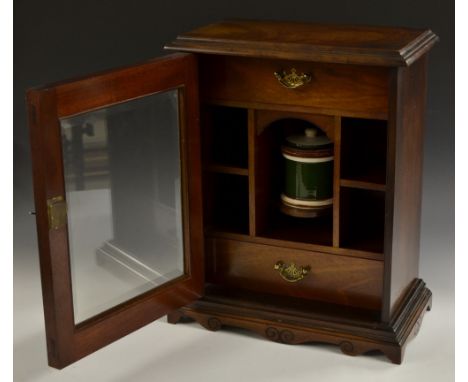 An Edwardian mahogany gentleman's smoker's compendium, moulded top above a singular bevelled door, enclosing a pair of drawer