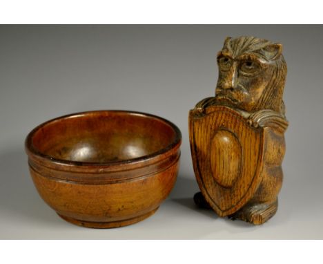 A 19th century oak finial, carved as a lion supporting a shield, 13cm high; a 19th century turned treen bowl, 12cm diam (2)