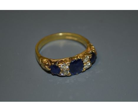 A seven stone sapphire and diamond ring, three graduating oval blue sapphire divided by two pairs of round brilliant cut diam