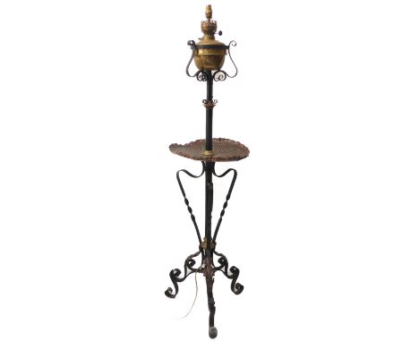 An unusual black-painted wrought-iron brass-mounted lamp standard; the hand-beaten circular copper tray above foliate-style m