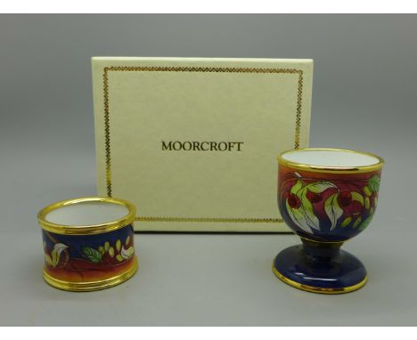 A Moorcroft handkerchief flower enamel egg cup and napkin ring, boxed 