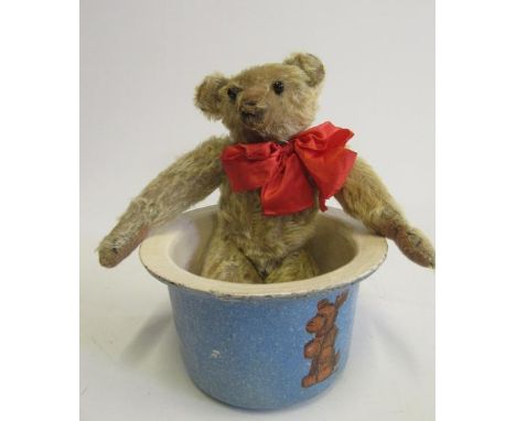 An early 20th century teddy bear, with straw filling, black button eyes, remnants of sewn nose, replaced felt paw pads, cloth