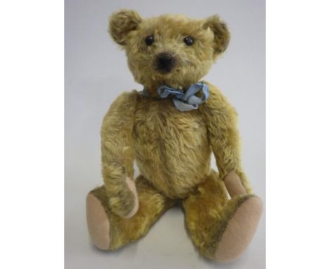 An old teddy bear, with black button eyes, rotating neck, shoulder and hip joints, sewn nose and mouth, and felt pads, 16 1/2