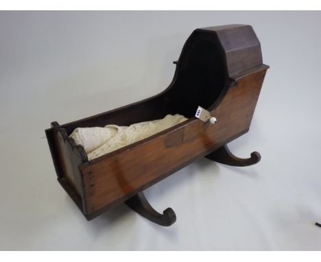 A Victorian mahogany doll's crib, with lobed foot piece, ceramic handles and oak rockers, 30 1/2" long (Est. plus 21% premium