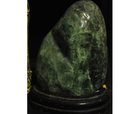 A large polished green jade specimen on a wooden base, H. 25cm