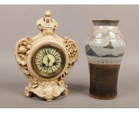 A pottery cased 8 day mantle clock with cylindrical movement, chiming on a bell along with a studio pottery vase.