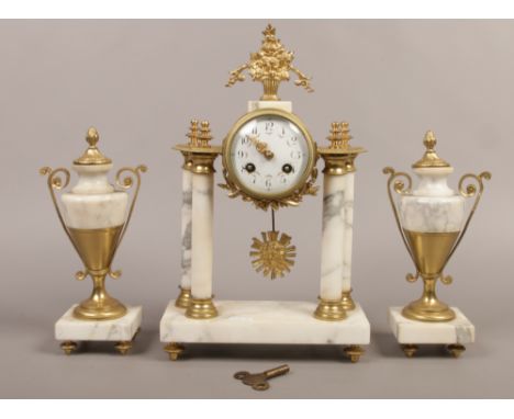 A French style brass and alabaster clock garniture with enamel dial and striking on a bell.