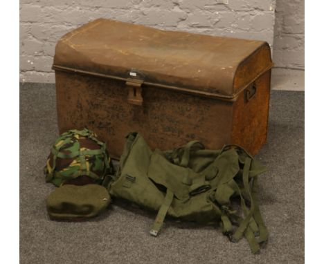 A twin handle tin trunk with contents of military equipment to include helmet, rucksack, cap etc.