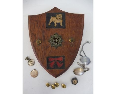 A Royal Army Service Corps cap badge and two buttons mounted on an oak shield.
