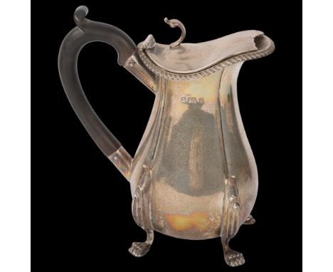 An Edwardian silver hot water jug, George Unite, Birmingham 1902, bulbous form with gadrooned rim, lion paw feet and ebonised