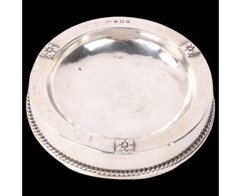 An Arts and Crafts George V silver ashtray, Albert Edward Jones, Birmingham 1928, circular form with flowerhead bosses and ro