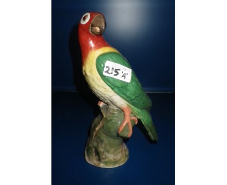 A CONTINENTAL CERAMIC PARROT with green wings standing on a rocky outcrop, with 'Sotheby's, Belgravia' label to the underside