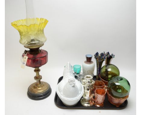 An early 20th Century oil lamp, with brass stem cranberry glass reservoir (cracked) and etched yellow glass shade; an opaque 