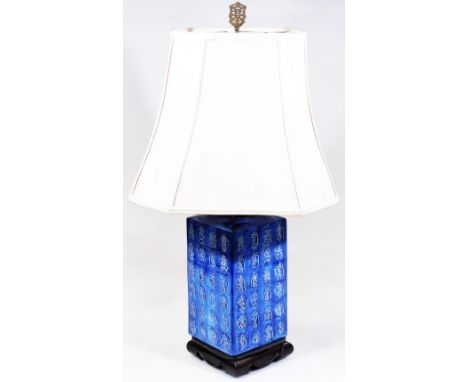 A Chinese semi porcelain table lamp, of square form set with various figures on a fixed ebonised base, with metal mounts and 