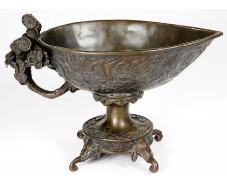 A Chinese patinated bronze vessel, with ellipse shaped bowl raised with geometric and floral patterns, with a floral handle o