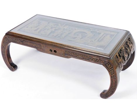 An early 20thC Chinese hardwood low table, heavily carved with figures, interior scenes, etc., on scroll legs, 35cm H, 94cm W