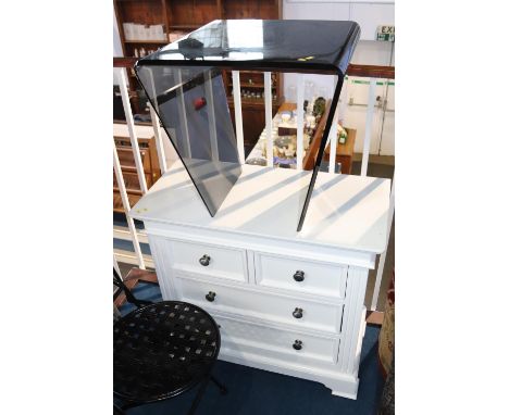 A smoked glass coffee table and a white chest of drawers
