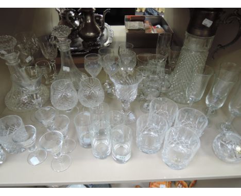 A shelf of cut-glass, including decanters, claret jug with plated jug and various drinking glasses