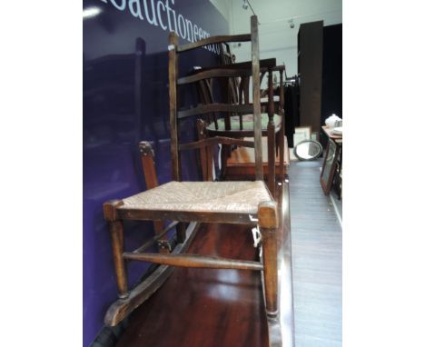 An early 20th century oak rocking chair having ladder back and rush seat