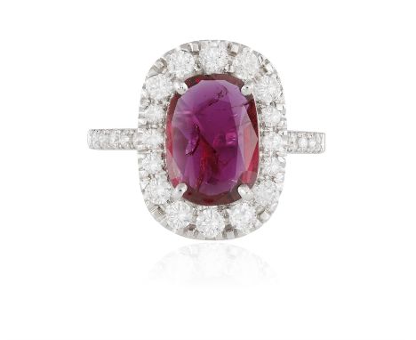 A RUBY AND DIAMOND CLUSTER RINGThe elongated cushion-shaped ruby weighing 2.08cts within a four-claw setting, to a brilliant-