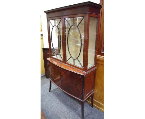 An Edwardian flame mahogany display cabinet, outswept cornice, two astragal glazed doors enclosing shelving to top, two panel