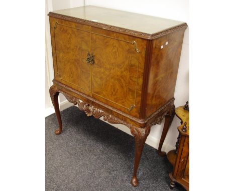 A reproduction walnut drinks cabinet, carved border with two doors pierced and carved apron and cabriole legs with club feet 