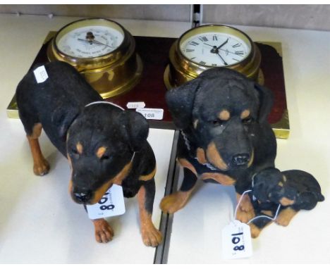 A brass clock and barometer mounted on backboard together with two models of Rottweilers (3)