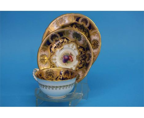 A Royal Worcester trio decorated by Jack Stanley painted with plums, cherries and apples with a cobalt blue and gilt border, 