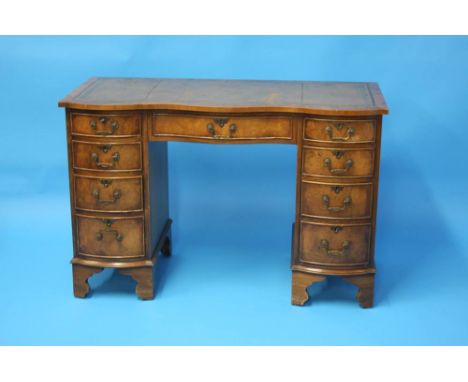 A reproduction mahogany ladies writing desk with leather inset top below a central drawer, flanked by four drawers to each pe