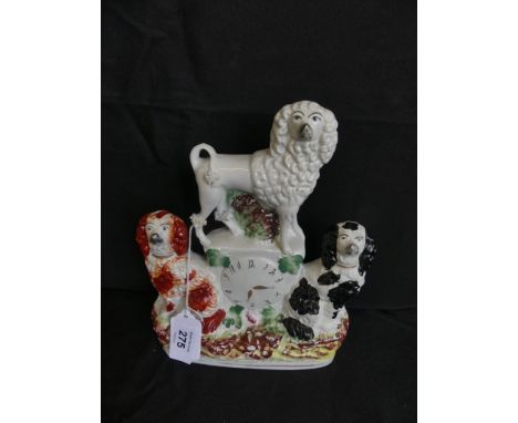 A 19th Century Staffordshire clock figure group, the central clock surrounded by two Spaniels and a Poodle, raised on a oval 