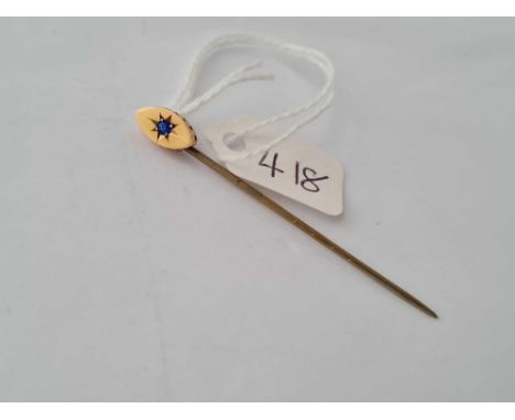 A oval topped stick pin with central sapphire set in gold