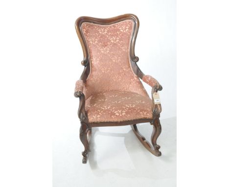 A Victorian mahogany button back rocking chair the shield shaped back above padded arms with scroll terminals and conforming 