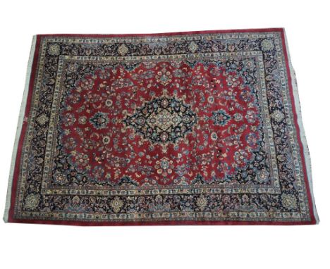 A Persian Kashan style medallion rugThe large rug on a predominantly ruby red ground with central arabesque style lozenge enc