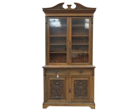 A Victorian oak library bookcaseWith a twin swan neck pediment above two glazed doors enclosing four shelves, flanked by chan