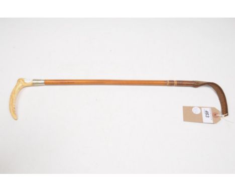 An Adeney and Swaine riding cropThe slender malacca stick with leather tab adorned with a caned antler handle and makers butt