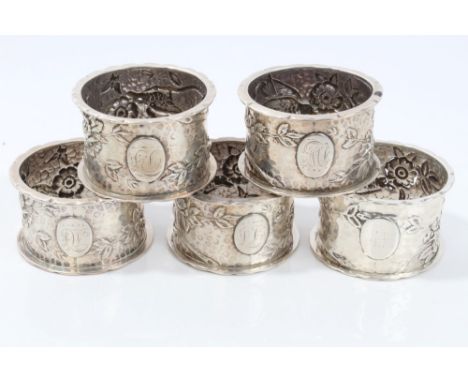 Four Victorian silver napkin rings of circular form, with naturalistic bird and floral decoration and flared rims (Birmingham