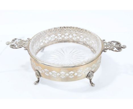 1920s silver butter dish of circular form, with cut glass liner and twin pierced cherub mask handles, on four paw feet (Londo