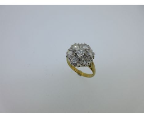 the central round brilliant cut diamond in raised claw setting above the six similar diamond petals, white metal setting to a