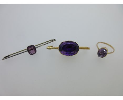 the first a short bar horizontally set to the centre with an oval cut amethyst in foiled, closed back mount, length 4.5cm, am